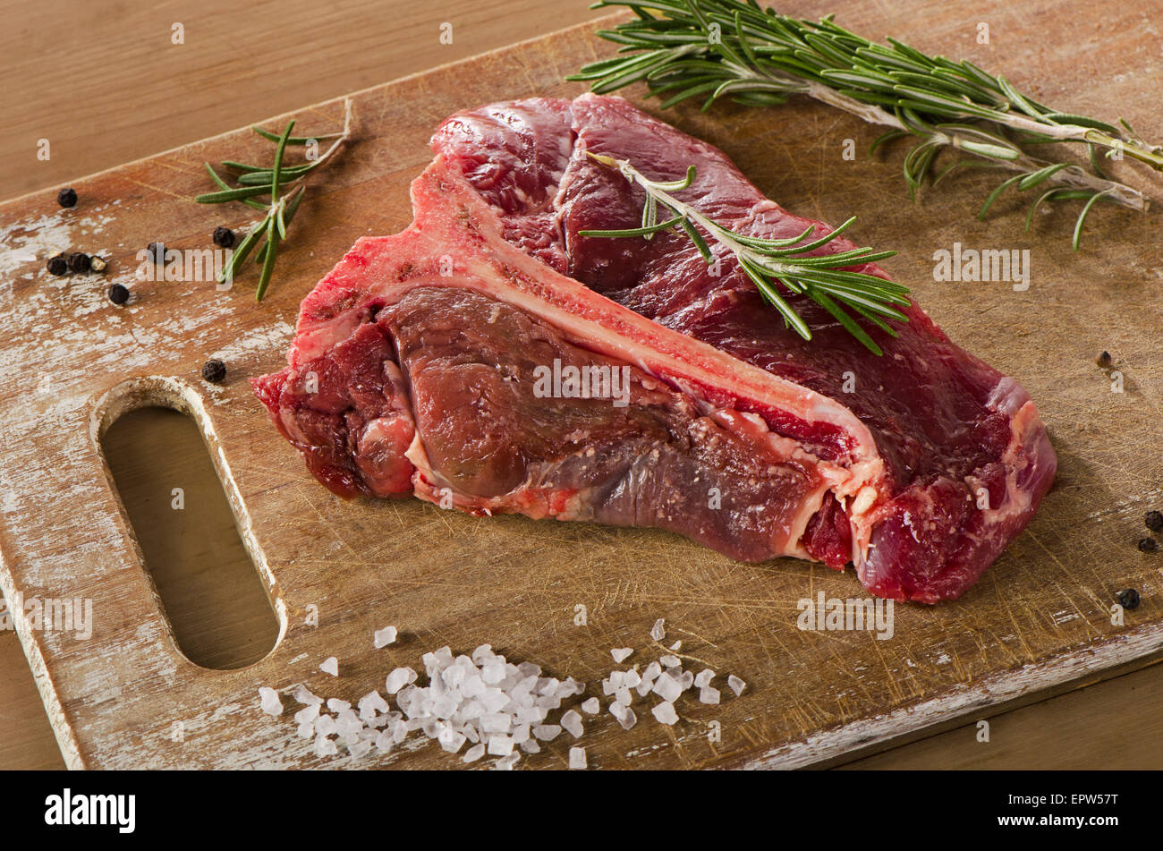 Le boeuf cru t-bone steak sur une vieille table en bois. Banque D'Images