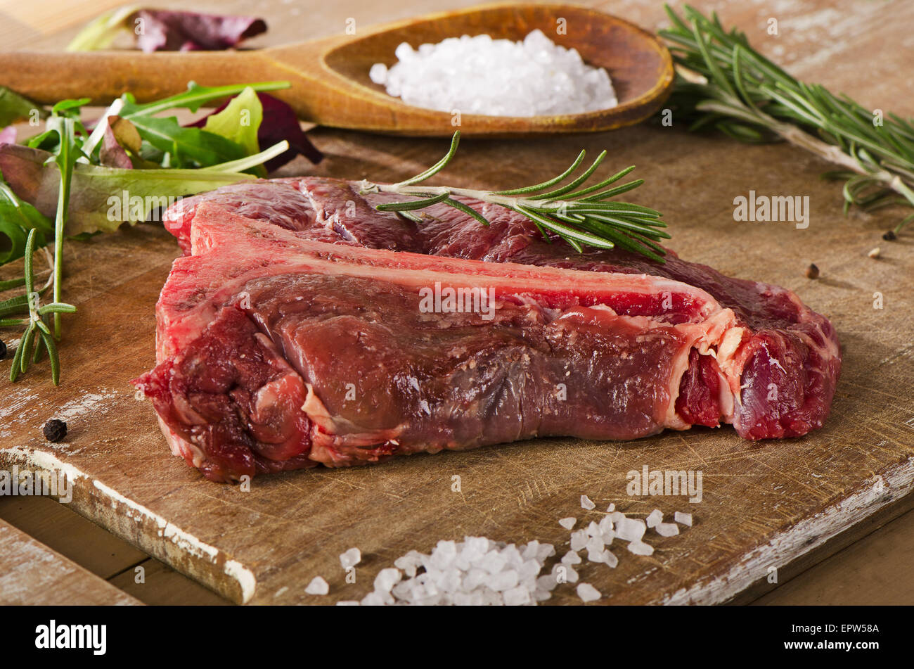 Le boeuf cru t-bone steak sur la vieille table en bois. Banque D'Images