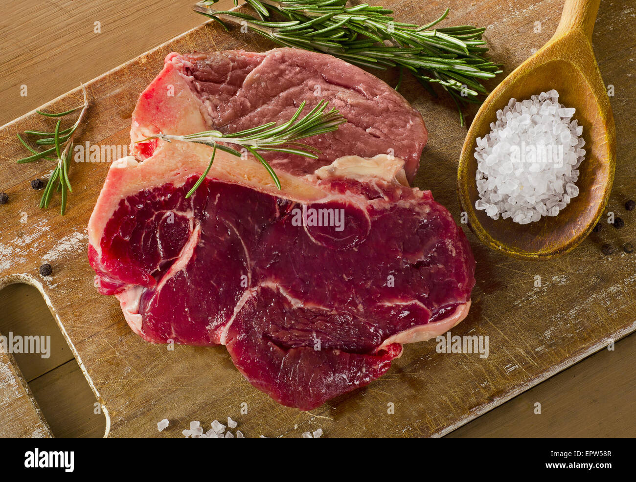 Le boeuf cru t-bone steak sur la vieille planche de bois. Banque D'Images