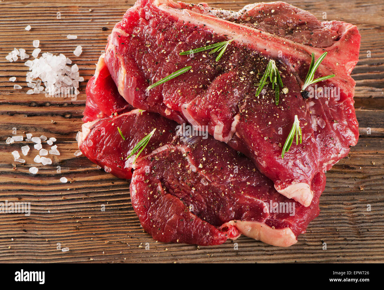 Pavé de boeuf avec des assaisonnements et des herbes fraîches sur planche de bois. Selective focus Banque D'Images