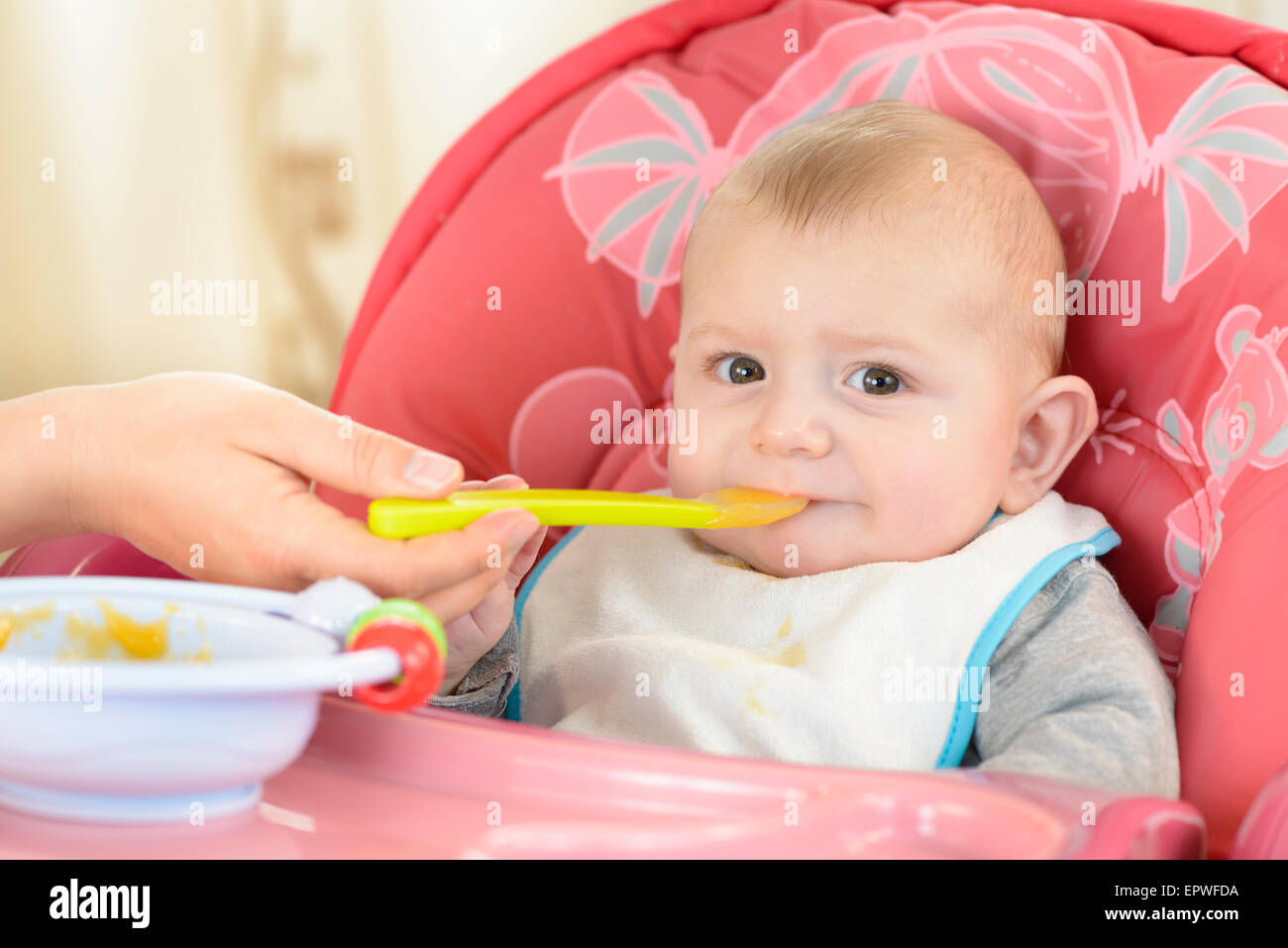 Baby Boy de manger dans une chaise haute à la maison Banque D'Images