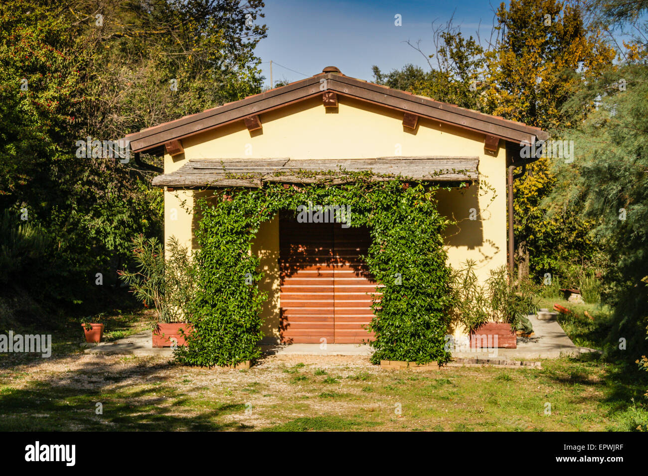 Petite maison de campagne dans la végétation et arbres générique dans les champs cultivés sous le gris-argent de ridge de craie badlands contexte en campagne italienne près de Brisighella en Emilie Romagne Banque D'Images