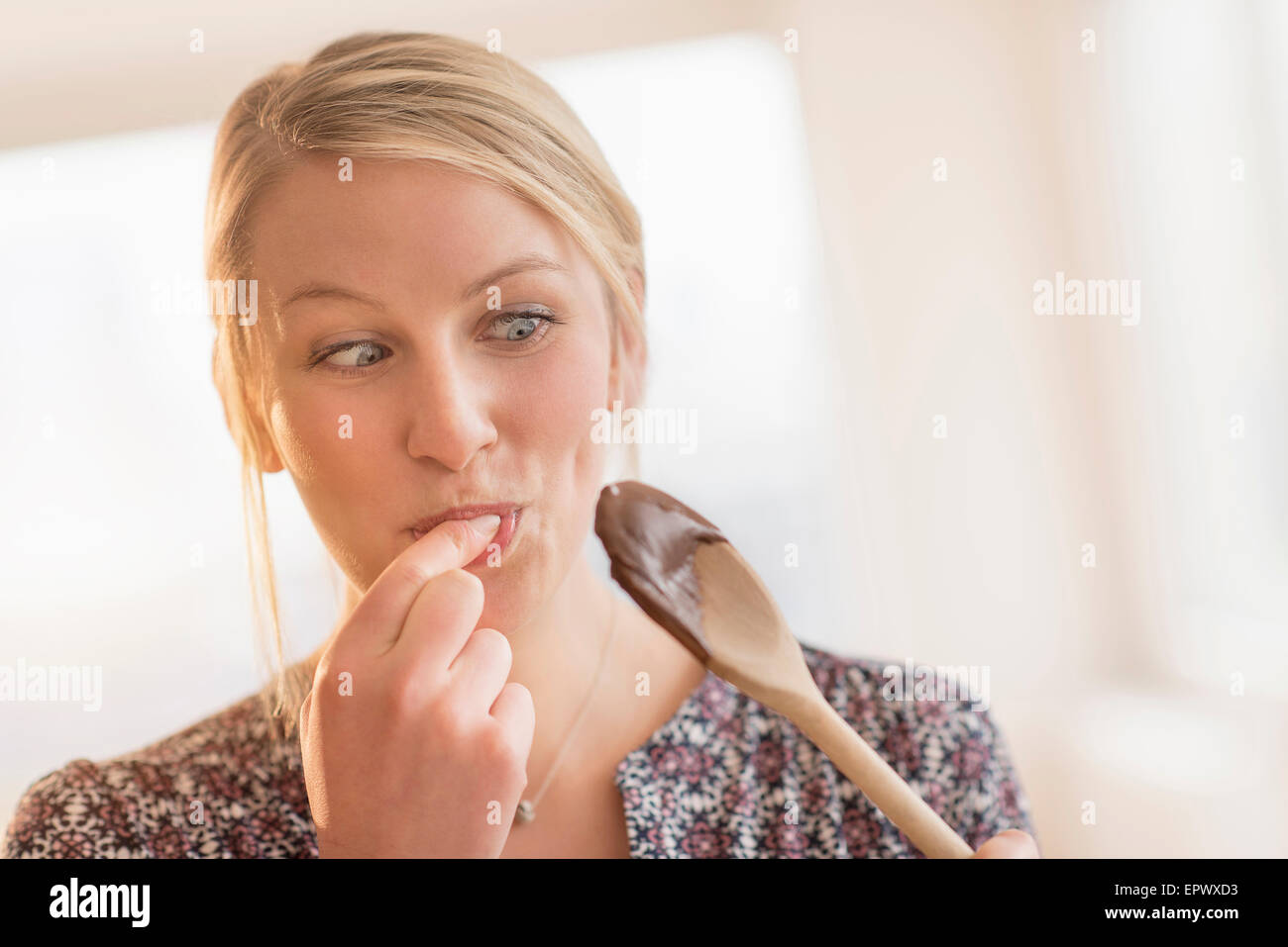 Woman licking batter off spoon Banque D'Images