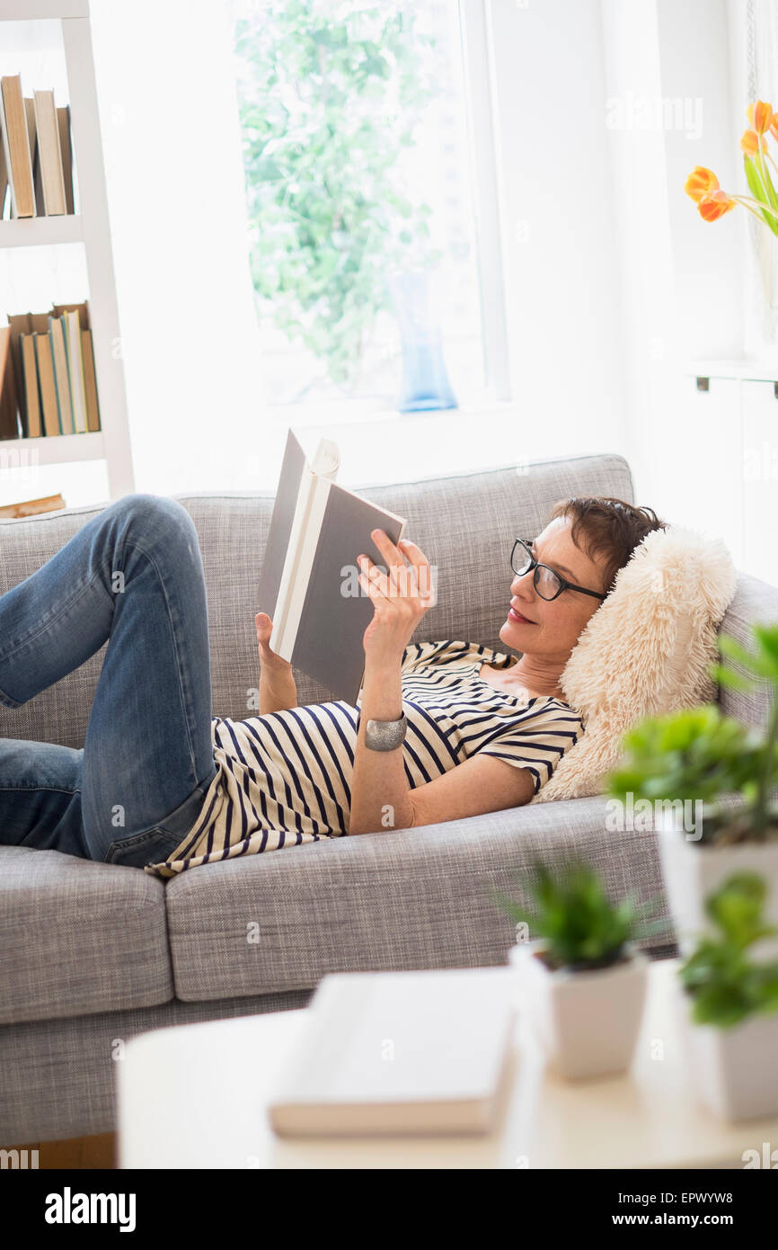 Senior woman reading book on sofa Banque D'Images