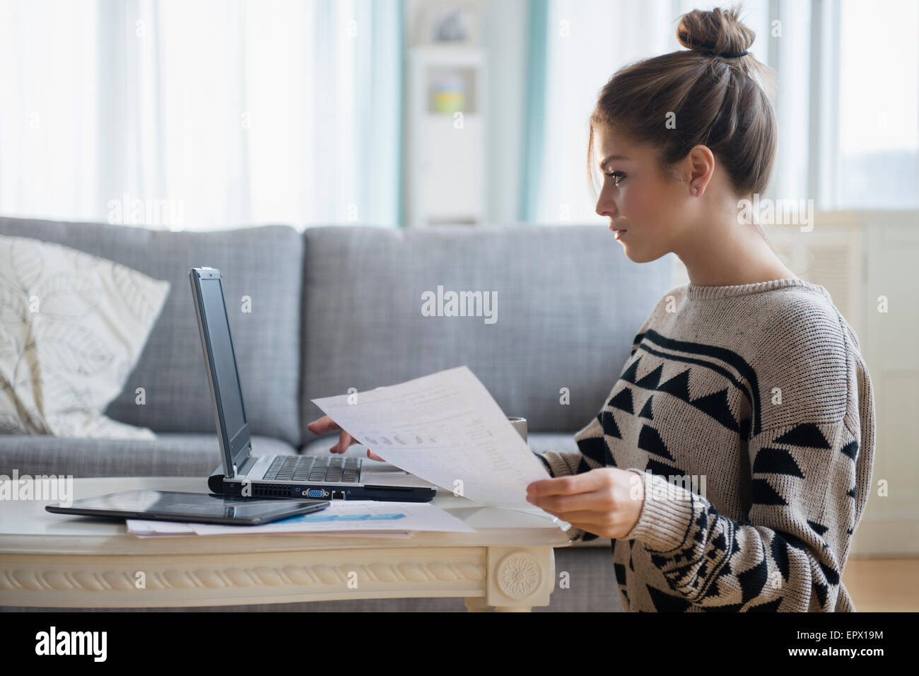 Jeune femme travaillant avec un ordinateur portable dans la salle de séjour Banque D'Images