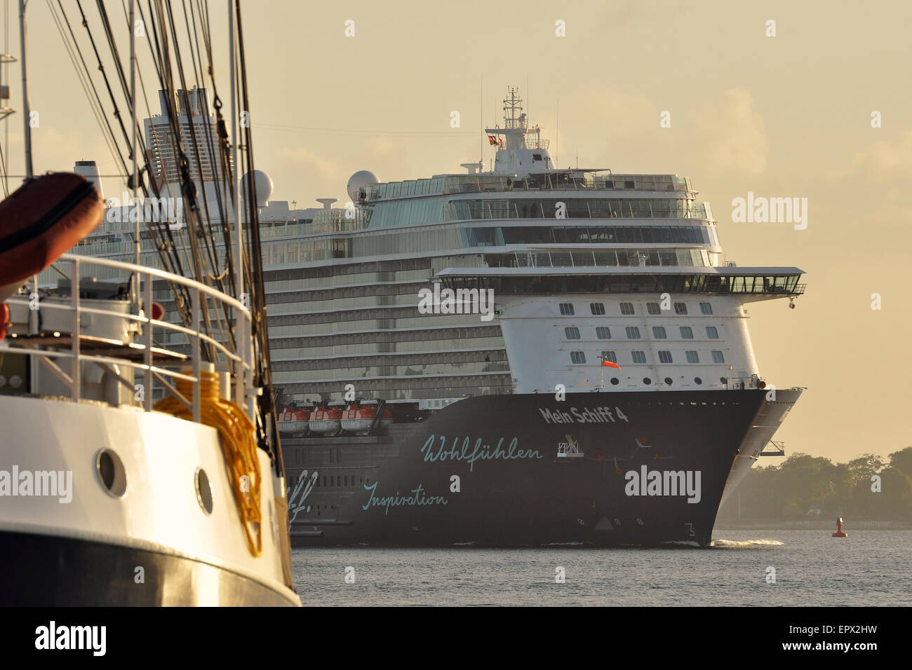 Cruiseship 'Mein Schiff 4' en passant un bateau à voile traditionnel dans le soleil matinal. Banque D'Images