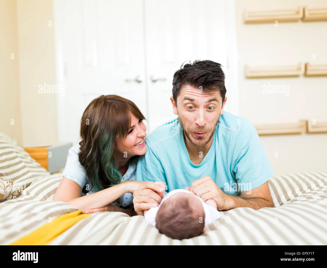 Heureux parents jouer avec bébé garçon (6-11 mois) on bed Banque D'Images