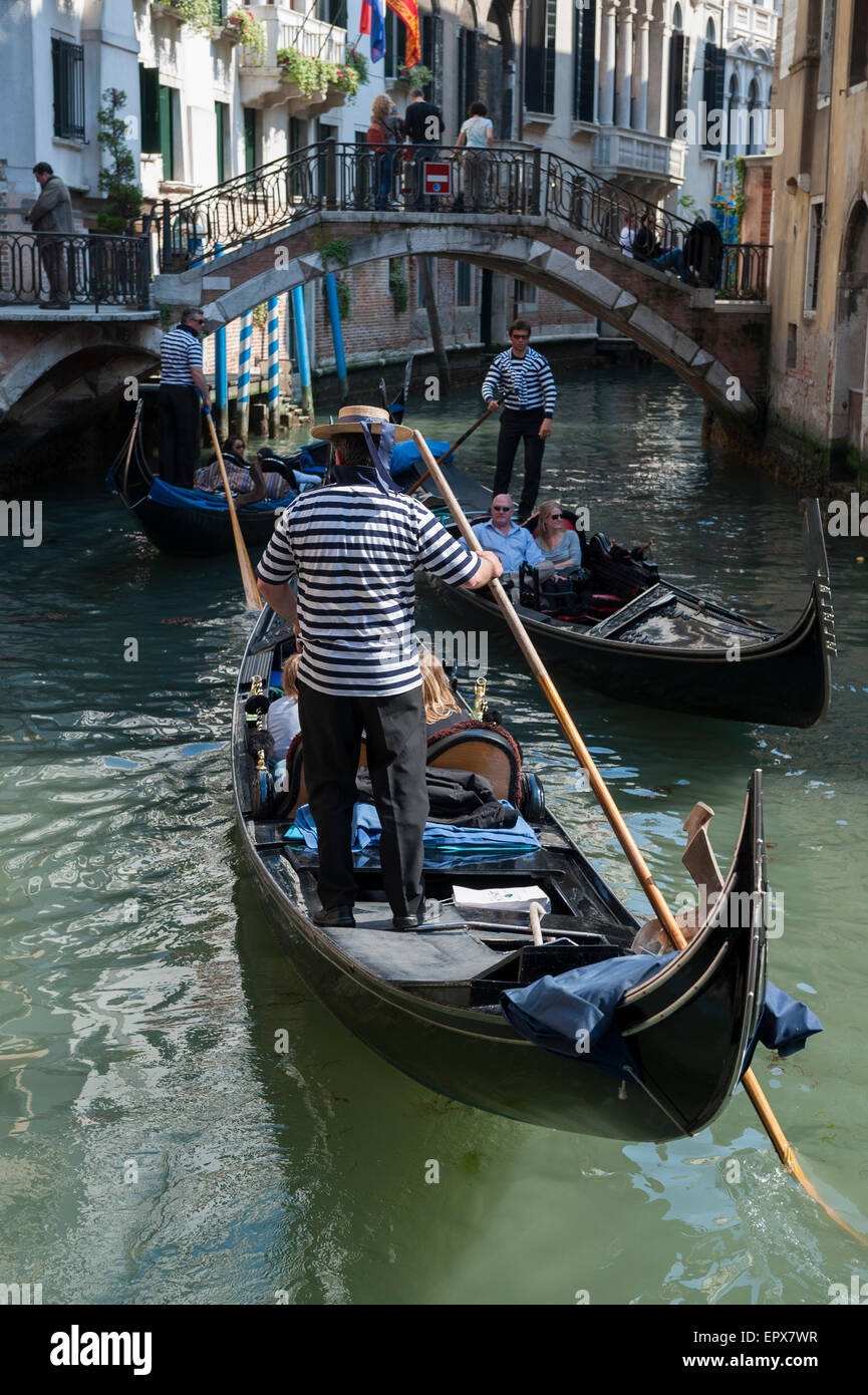 Venise, Italie - 24 avril 2013 : Venetian gondola gondolier plates son passé un autre sur un petit canal. Banque D'Images