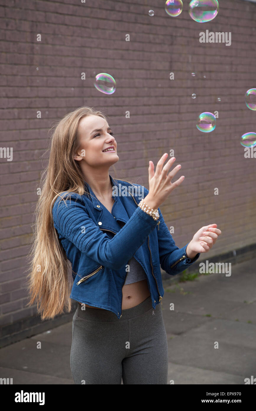 Pretty woman attraper des bulles de savon à l'extérieur. Banque D'Images