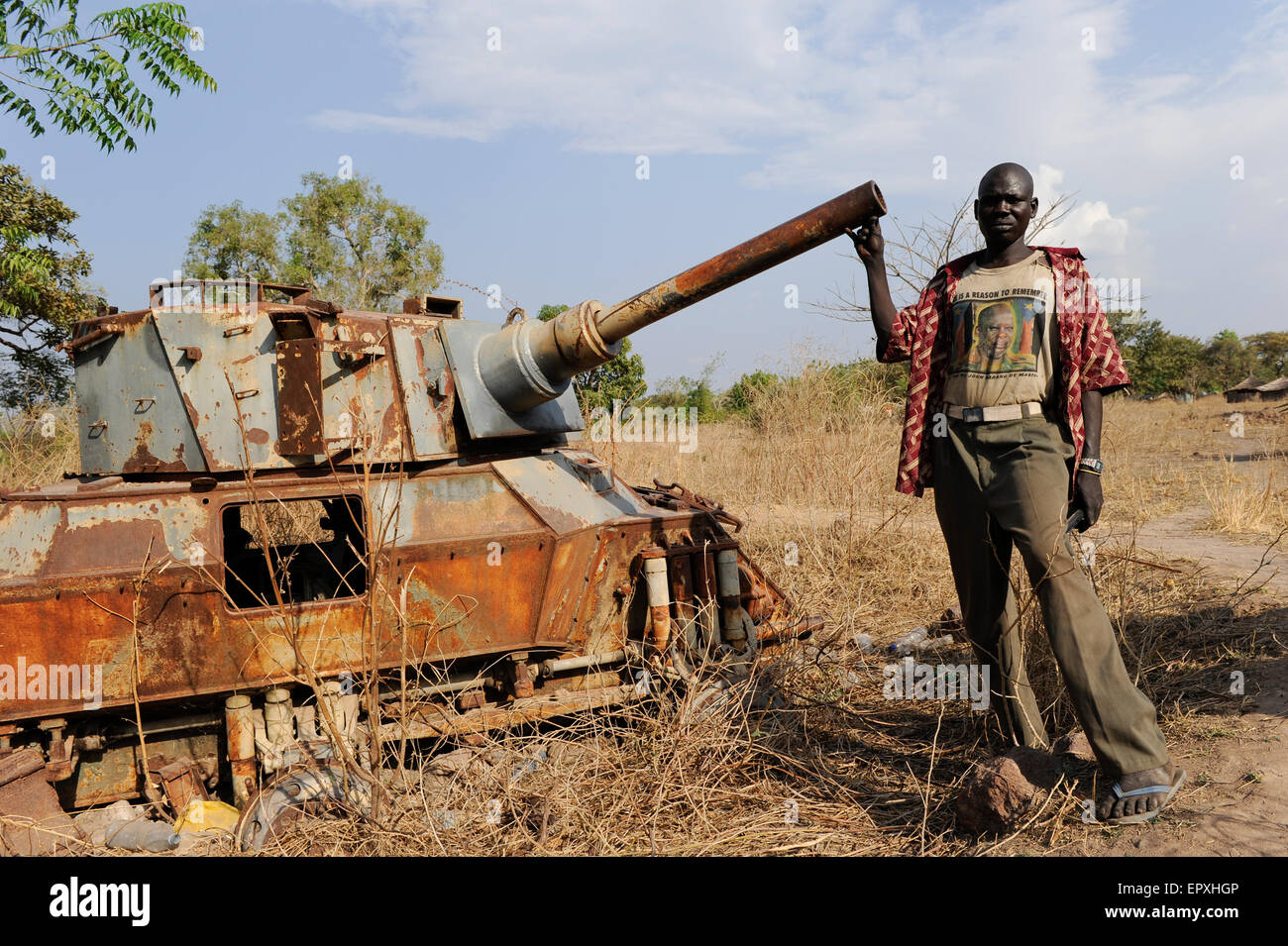 Soudan du Sud, État des Lacs, Rumbek, épave du véhicule blindé à six roues FV601 Saladin, fabriqué par l'usine Alvis à Coventry, Royaume-Uni, le char a été capturé par l'armée de libération sud-soudanaise SLPA des Forces armées soudanaises SAF pendant la seconde guerre civile soudanaise de 1983 à 2005, homme avec T-shirt avec l'image de John Garang l'ancien chef de la SPLA et héros national aujourd'hui Banque D'Images