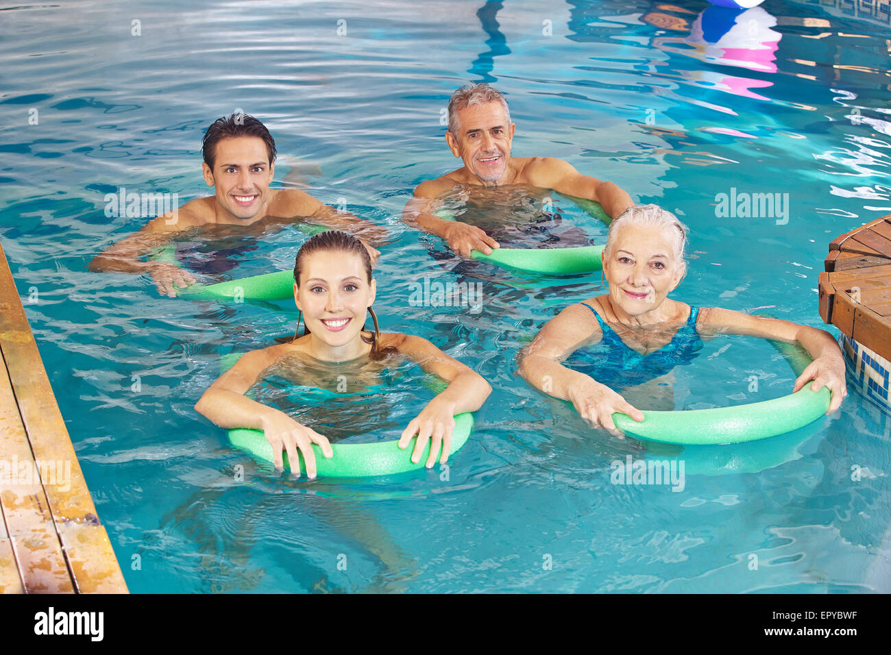 Groupe de gens heureux avec nouilles faire nager en classe aqua fitness piscine Banque D'Images