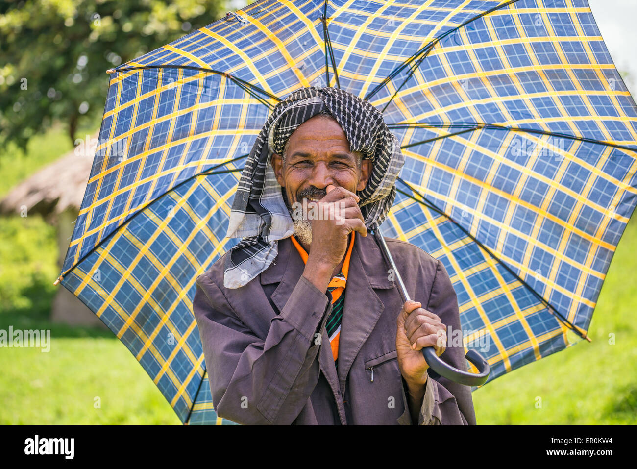 Vieux homme éthiopien avec un parapluie sur une journée chaude. Banque D'Images