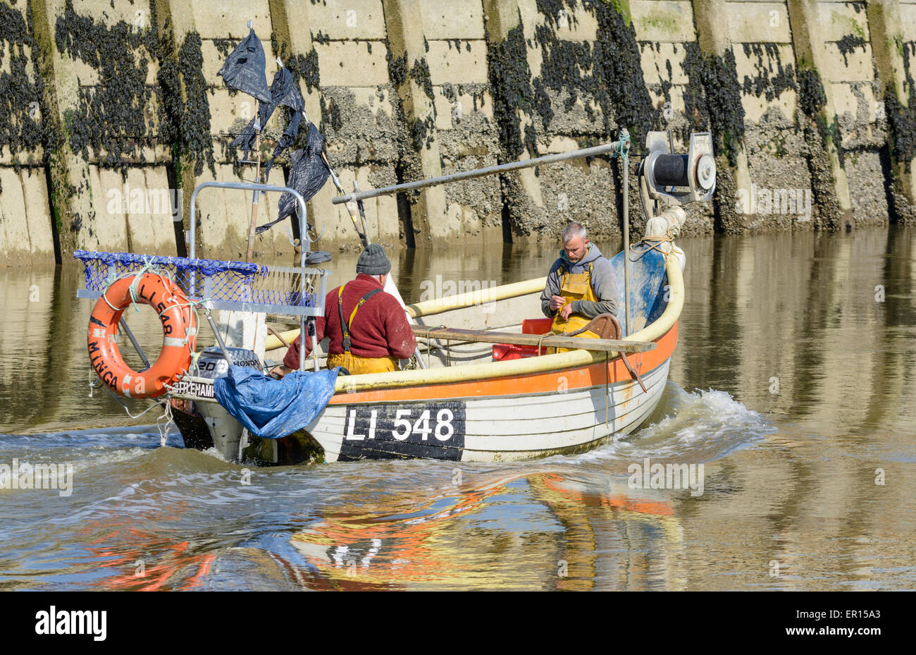 Personnes dans un petit bateau en bois sur la rivière après un voyage de pêche. Banque D'Images