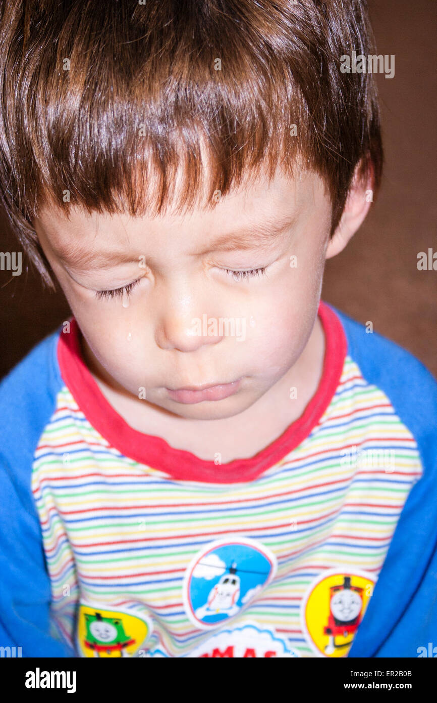 Gros plan de la tête et de l'épaule de jeune enfant, garçon, 3-4 ans, contrarié et pleurant avec des larmes roulantes des joues. Race mixte, caucasien-asiatique. Banque D'Images