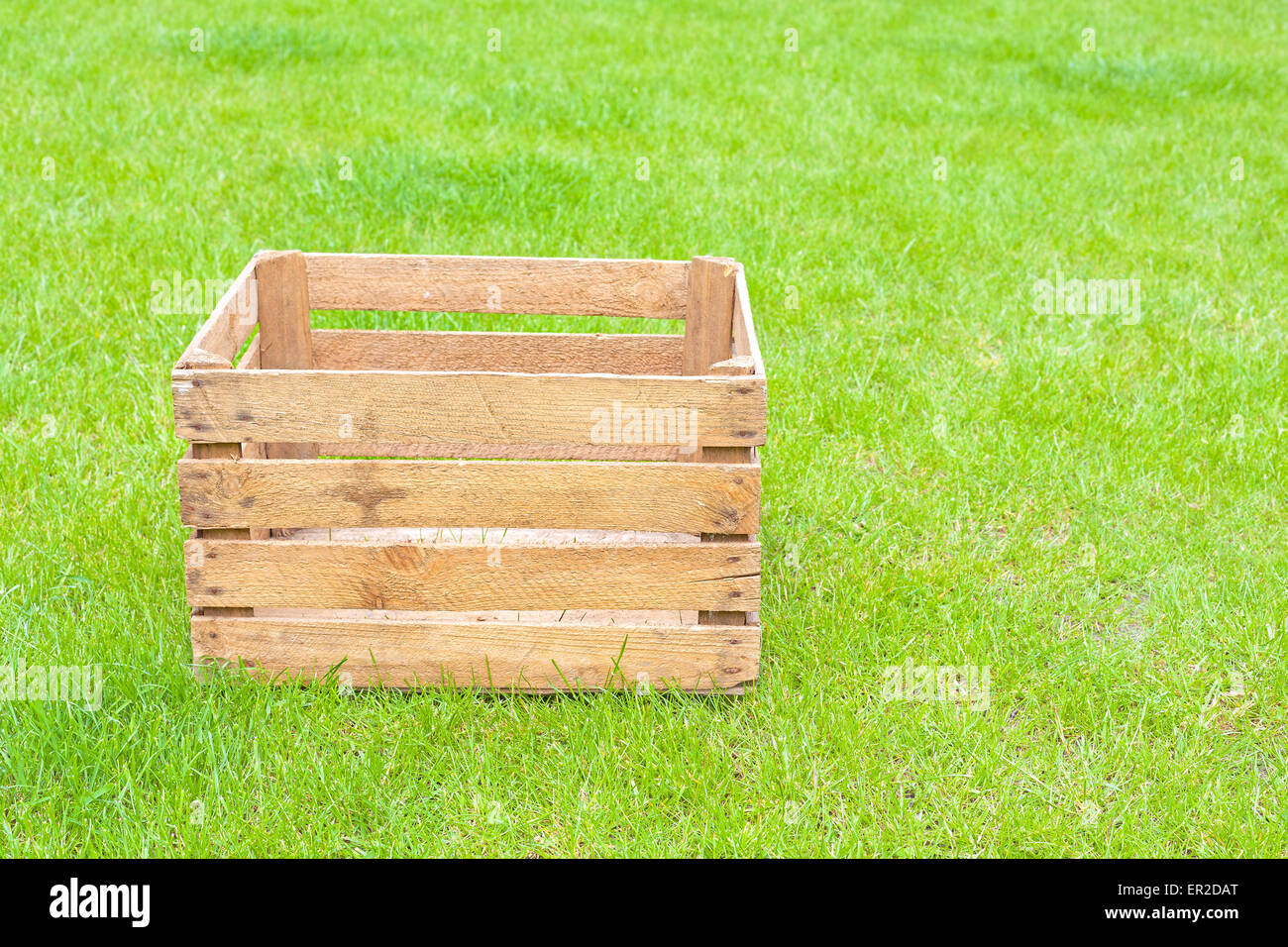 Boîte en bois vide sur l'herbe verte, de l'espace pour le texte. Banque D'Images