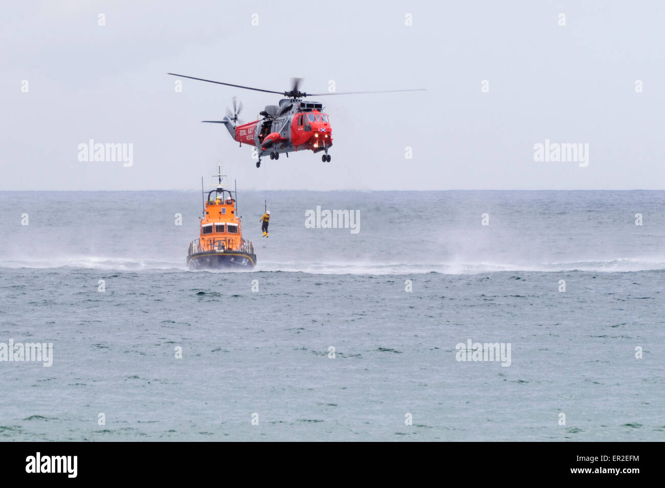 Les treuils d'un hélicoptère à bord d'un homme comme le sauvetage RNLB attend. Banque D'Images