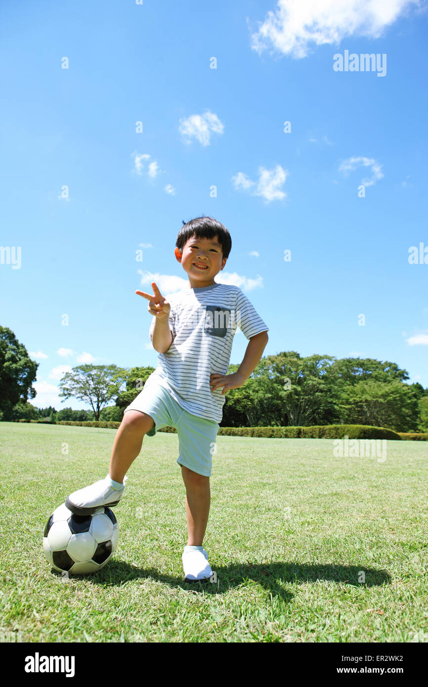 Jeune garçon japonais joue au soccer dans un parc de la ville Banque D'Images