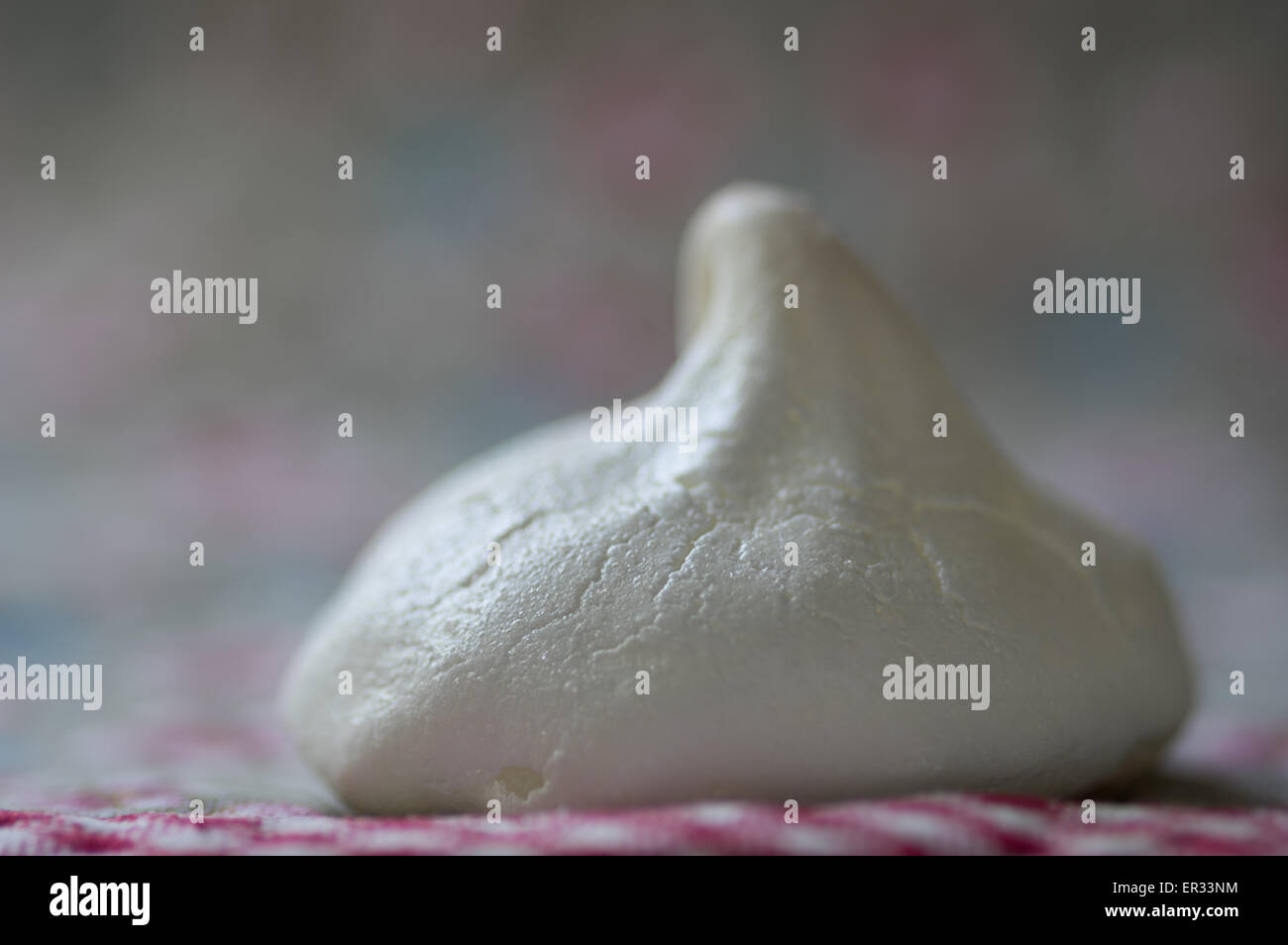 Close up of tentant home made meringue sur torchon floral imprimé vichy. Banque D'Images