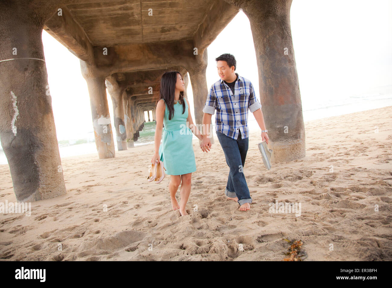 Couple Holding Hands, marche pieds nus sous une jetée Banque D'Images