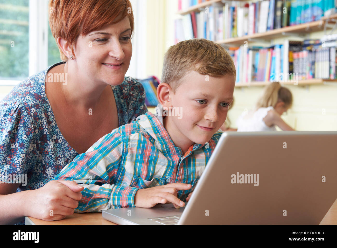 Élève de l'école avec l'aide de l'enseignant en classe d'ordinateur portable Banque D'Images