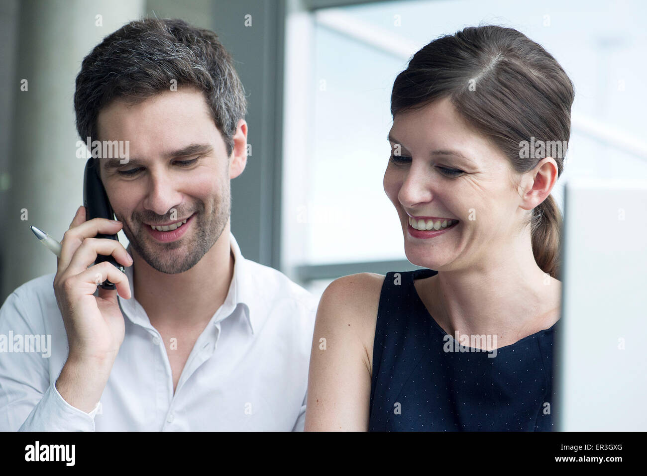 Des collègues d'affaires smiling together, man talking on cell phone Banque D'Images