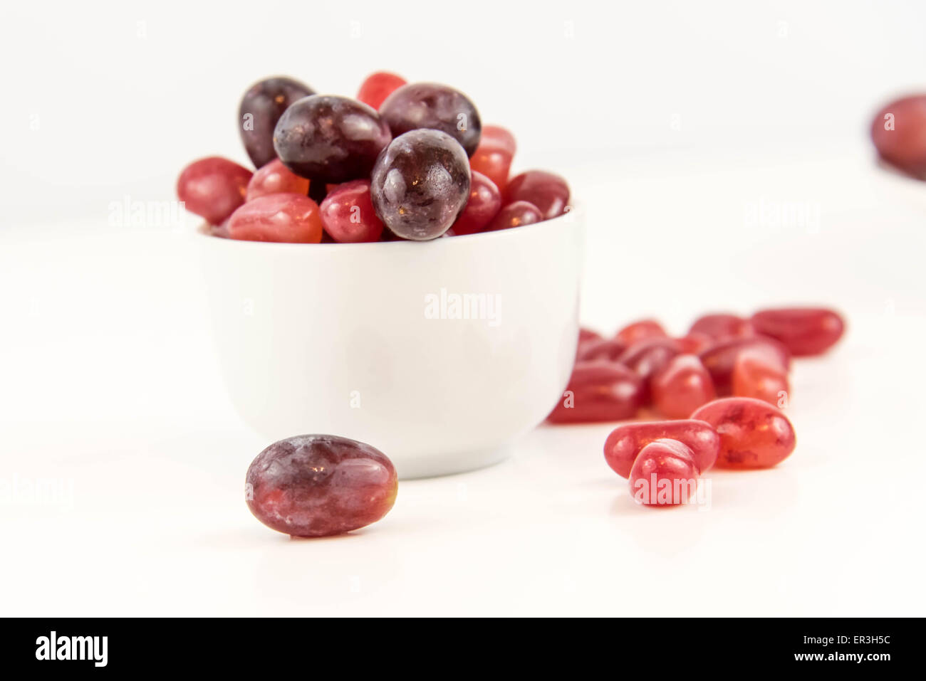 Les raisins de pourpre violet vs jelly beans - snack-décision entre aliments sains ou junk food Banque D'Images