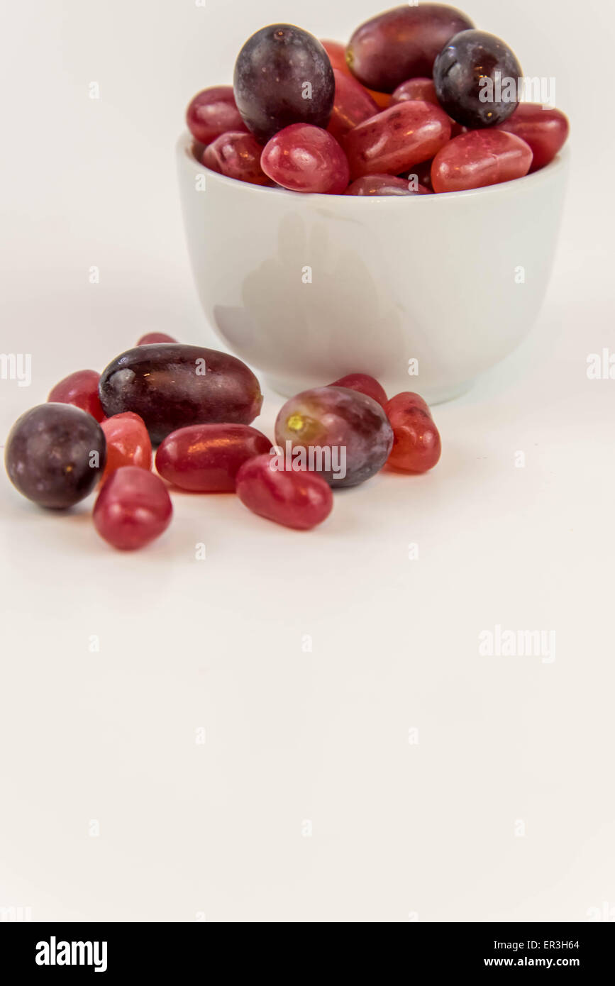 Les raisins de pourpre violet vs jelly beans - snack-décision entre aliments sains ou junk food Banque D'Images