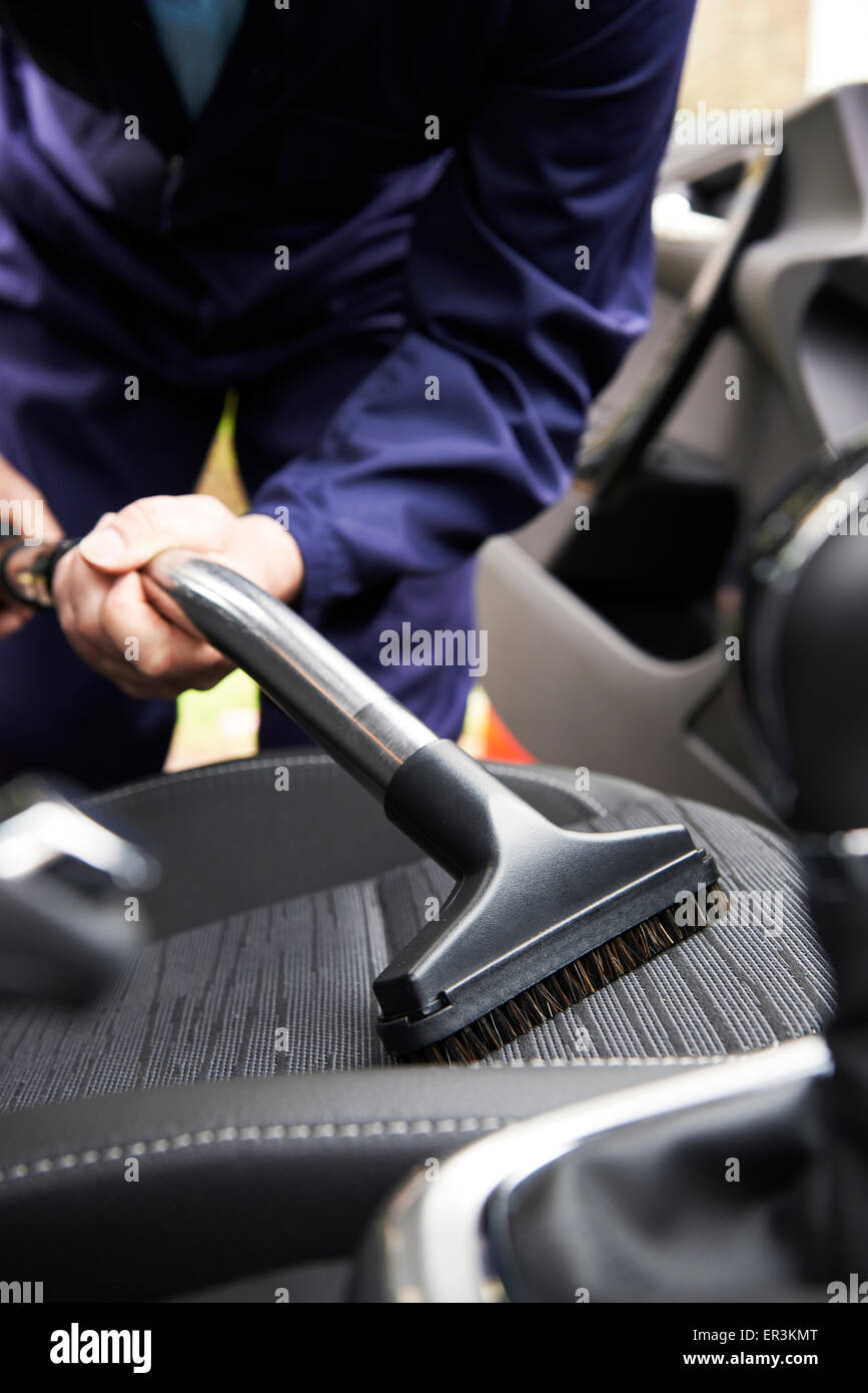 Man Hoovering siège de voiture pendant le nettoyage de voiture Banque D'Images