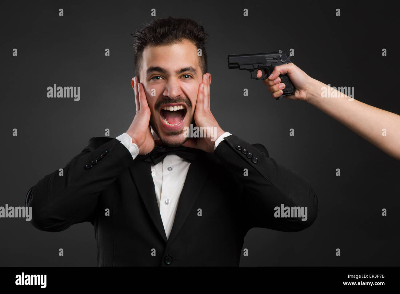 Man yelling avec une arme pointant sur sa tête Banque D'Images