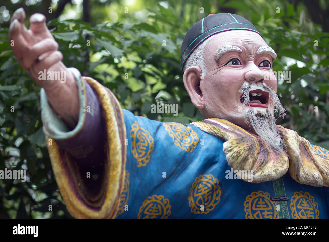 Un vieil homme en costume traditionnel chinois indique la direction à la main Banque D'Images