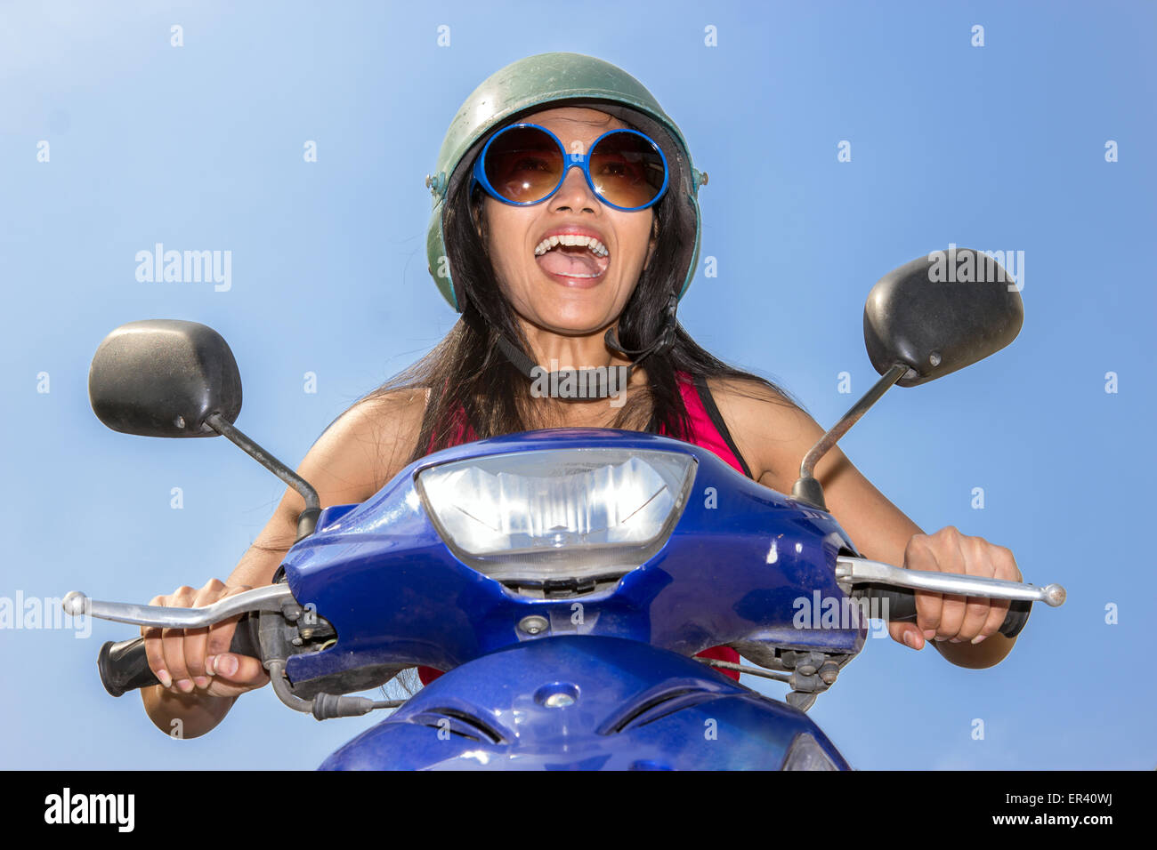 Vue de face d'une femme assise sur un scooter sur un fond bleu Banque D'Images