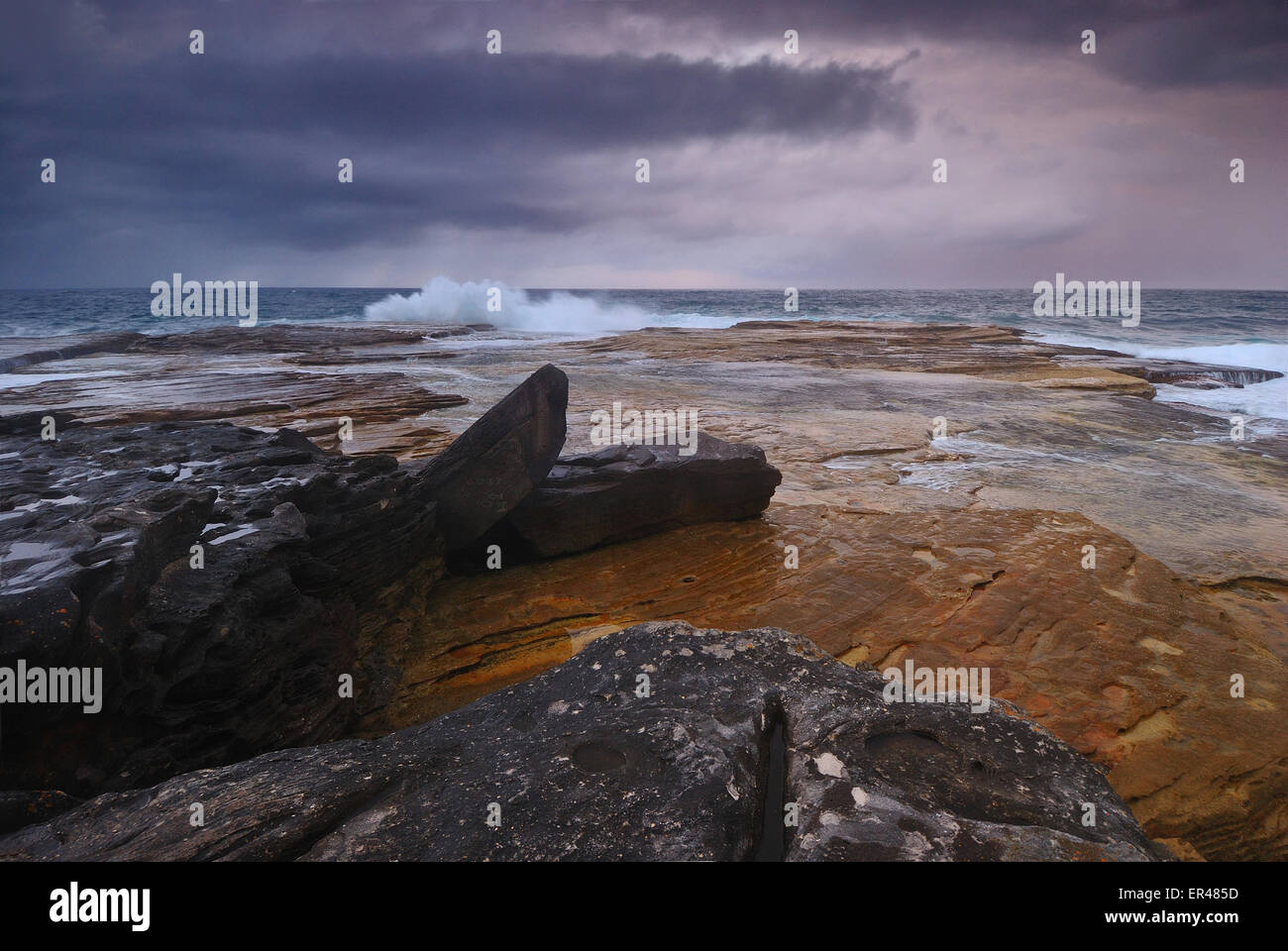 Seascape rocheux scène avec lever du soleil de l'océan lointain et les roches de couleur sur l'avant-plan Banque D'Images