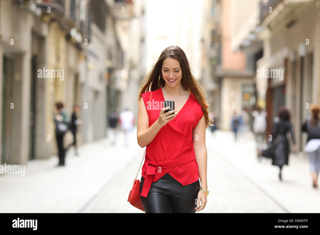 Vue de face d'une mode femme heureuse la marche et à l'aide d'un téléphone  intelligent sur une rue de la ville Photo Stock - Alamy