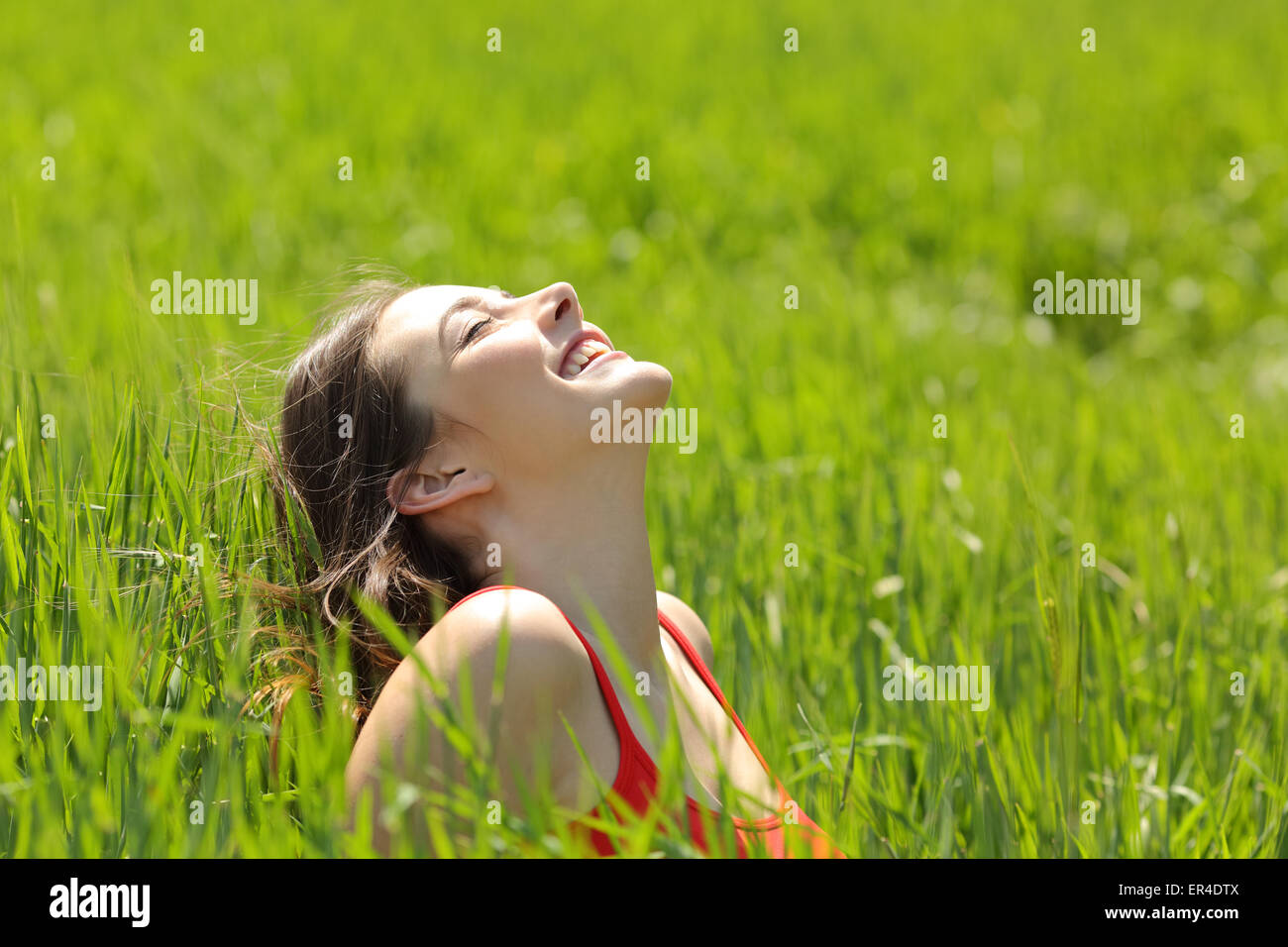 Happy girl face à respirer l'air frais et profiter du soleil dans un pré dans une journée ensoleillée d'été Banque D'Images