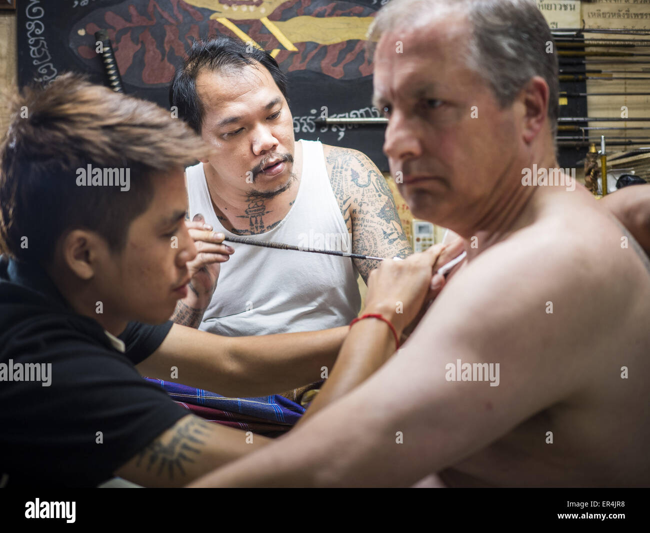 Bangkok, Thaïlande. 27 mai, 2015. AJARN NENG ONNUT, donne une sacrée Sak Yant tattoo à John, un visiteur de la Thaïlande en provenance des États-Unis. Ajarn Neng est un maître vénéré de tatouages sacrés et voit des gens toute la journée à son domicile de Bangkok. Sak Yant (Thai pour ''les tatouages des dessins mystiques'' sak =tatouage, yantra =dessin mystique) Les tatouages sont populaires à travers la Thaïlande, Cambodge, Laos et Myanmar. Les tatouages sont censées donner des pouvoirs magiques pour les personnes qui les ont. Les gens se les tatouages à répondre à des besoins spécifiques. Credit : ZUMA Press, Inc./Alamy Live News Banque D'Images