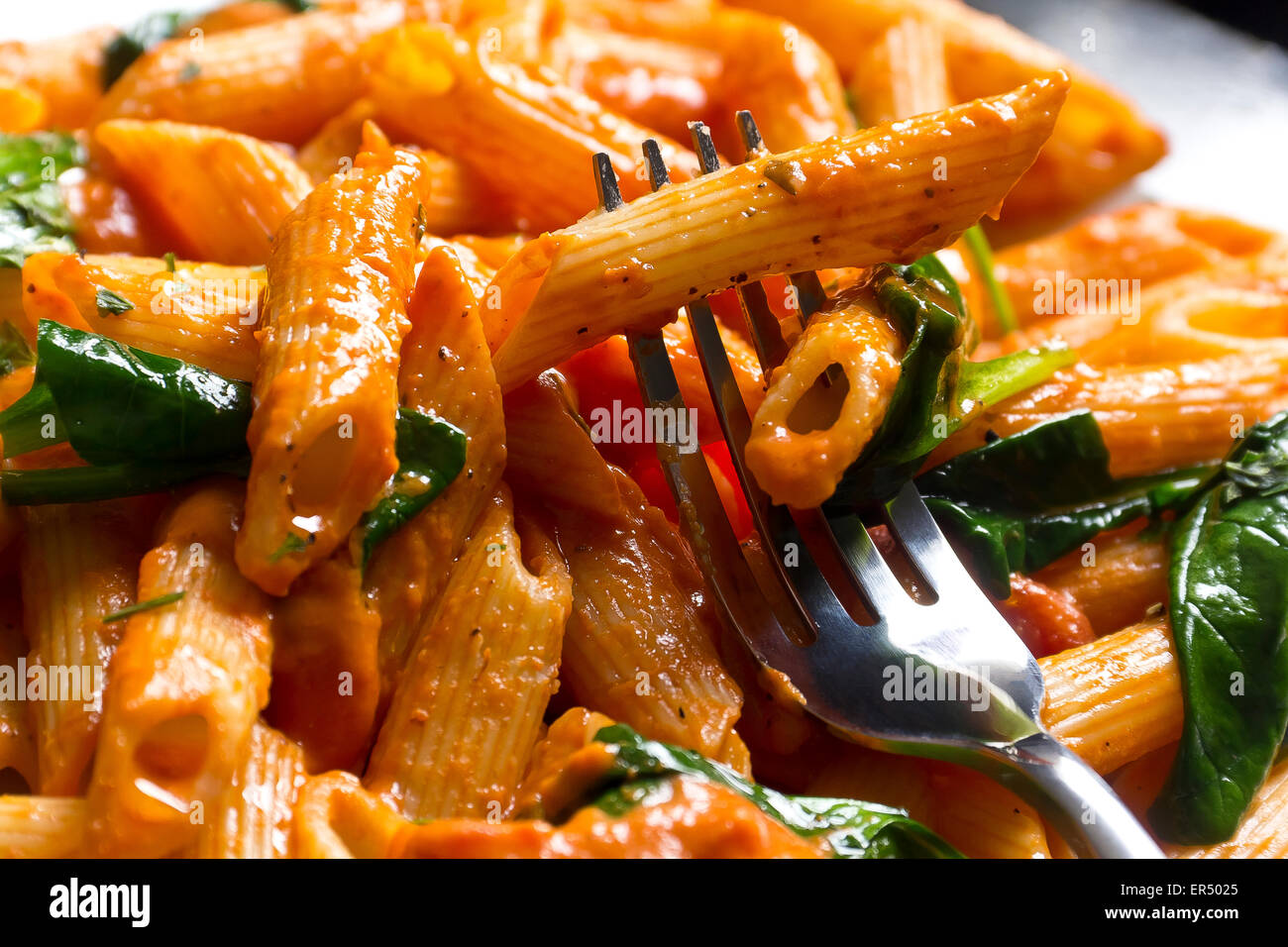 Pâtes penne à la vodka crème sauce tomate avec feuilles d'épinards sautés. Banque D'Images