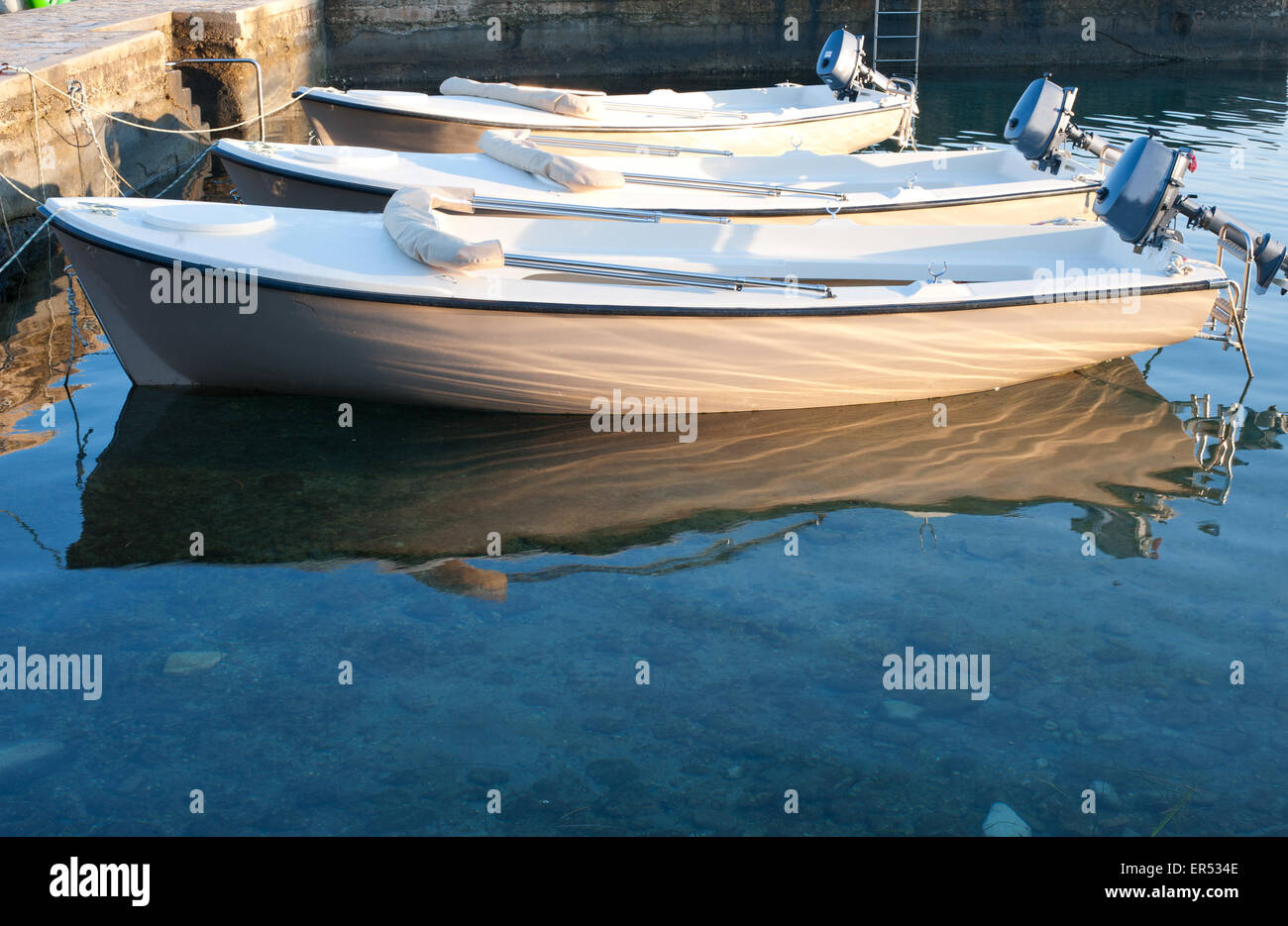 Trois bateaux près de l'eau de mer claire et jetée Banque D'Images