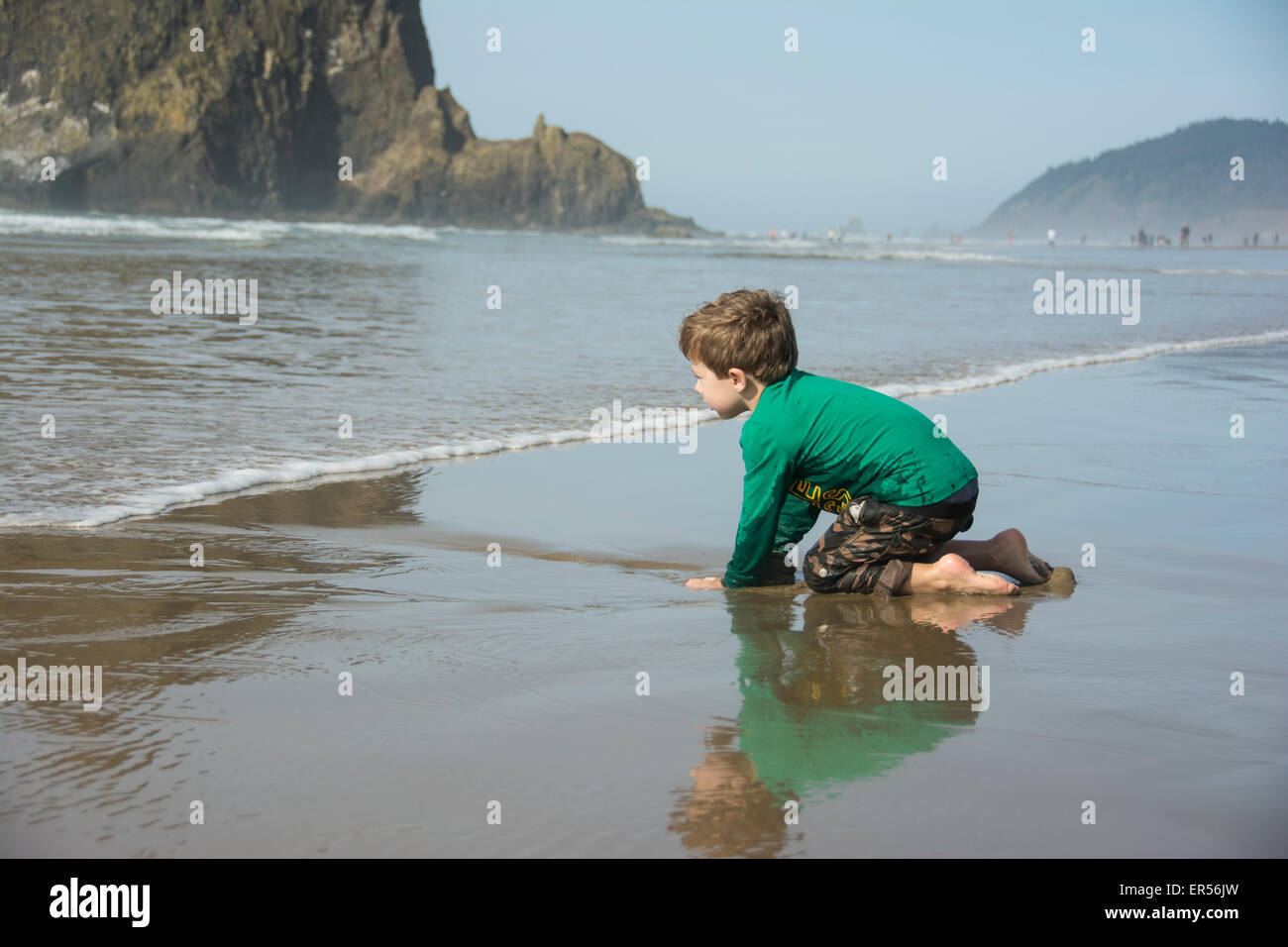 Bébé garçon creuse dans le sable et attend les vagues sur Cannon Beach, Oregon. Banque D'Images