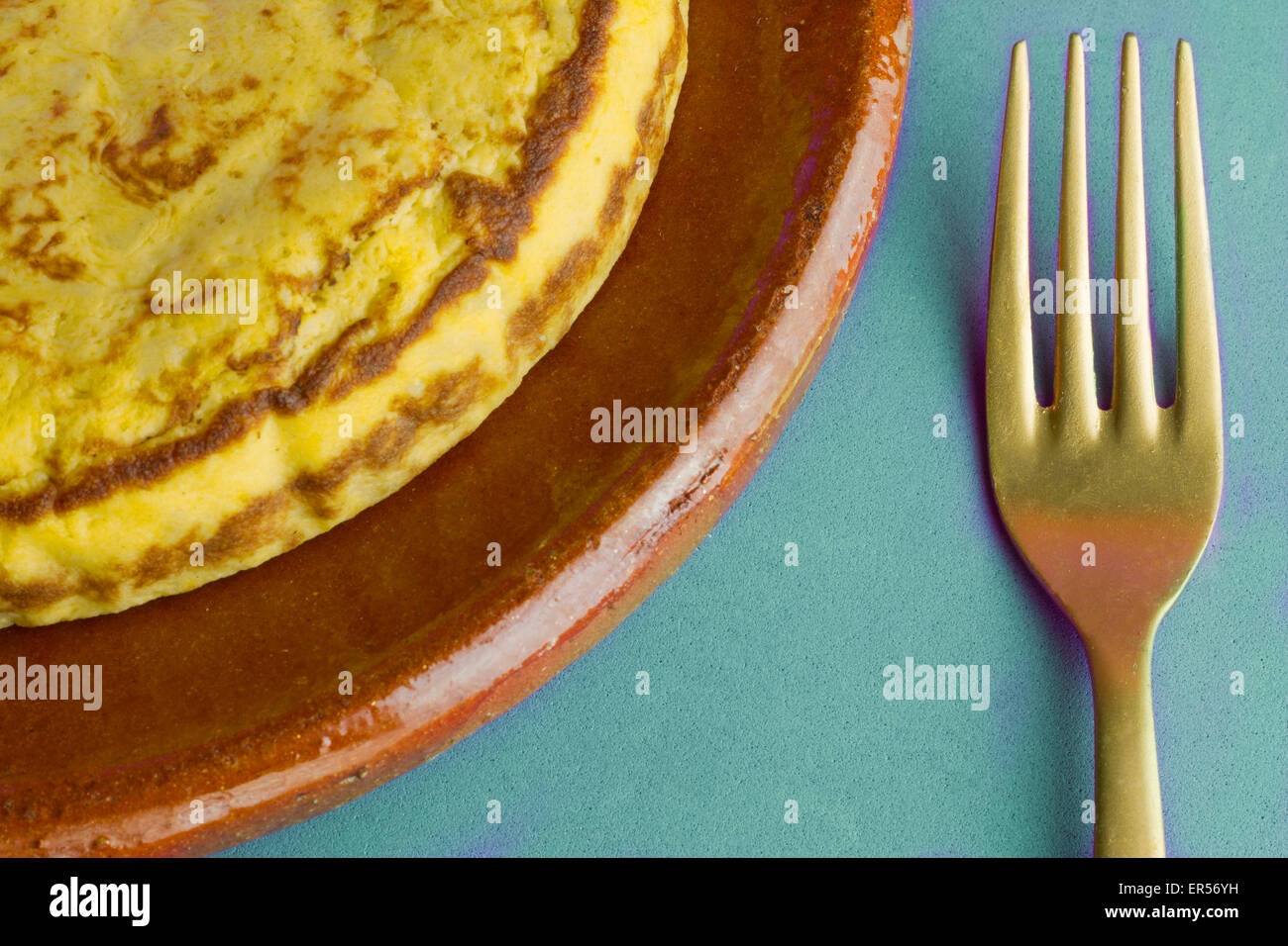 L'omelette espagnole et de la fourche d'or sur fond bleu Banque D'Images