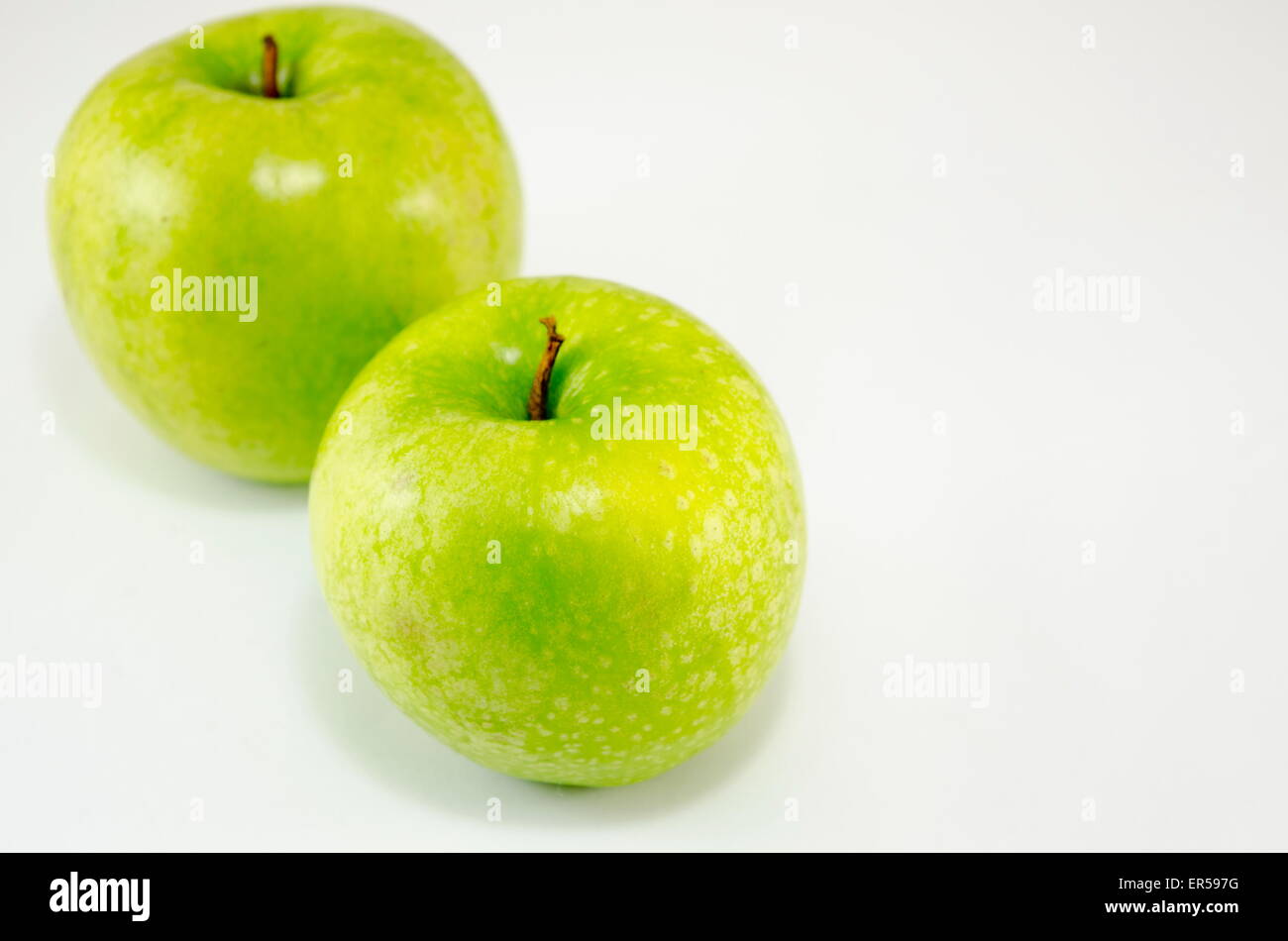 Deux pommes vertes appuyé contre l'un l'autre on white Banque D'Images