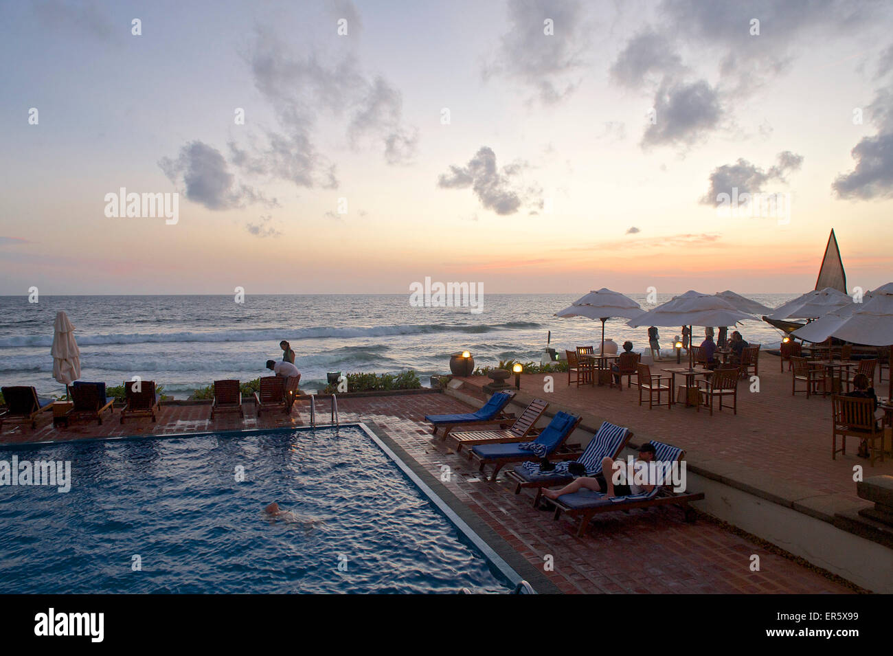 Les gens autour de la piscine avec vue sur la mer au crépuscule au Galle Face Hotel, Colombo, Sri Lanka Banque D'Images