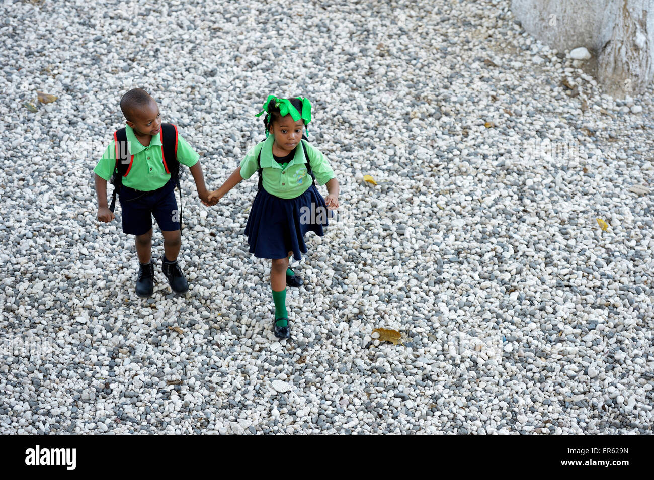 Garçon et fille, frères et sœurs, se tenant la main sur le chemin de l'école maternelle, Port-au-Prince, Haïti, Département de l'Ouest. Banque D'Images