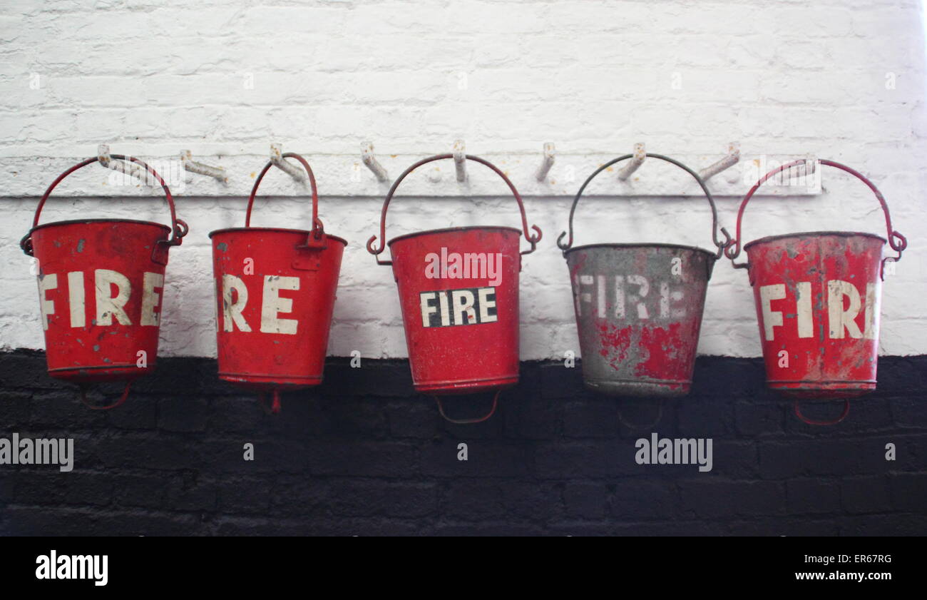Une rangée de seaux d'incendie vintage accrocher de suite, England, UK Banque D'Images
