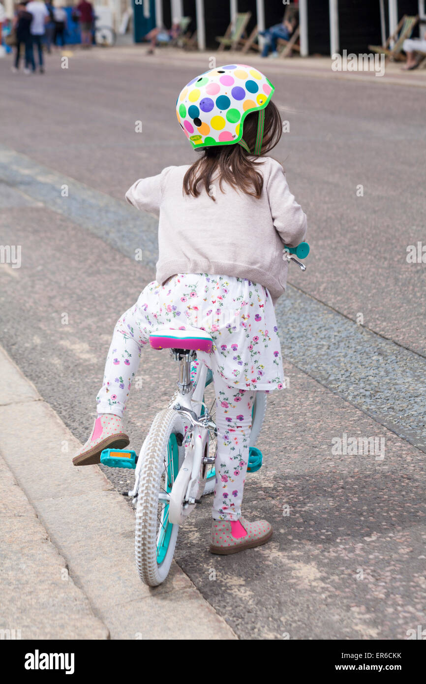 Jeune fille en vélo portant robe de contrepartie et des jambières et un casque de vélo sur la promenade boutonneuses à Bournemouth en mai Banque D'Images