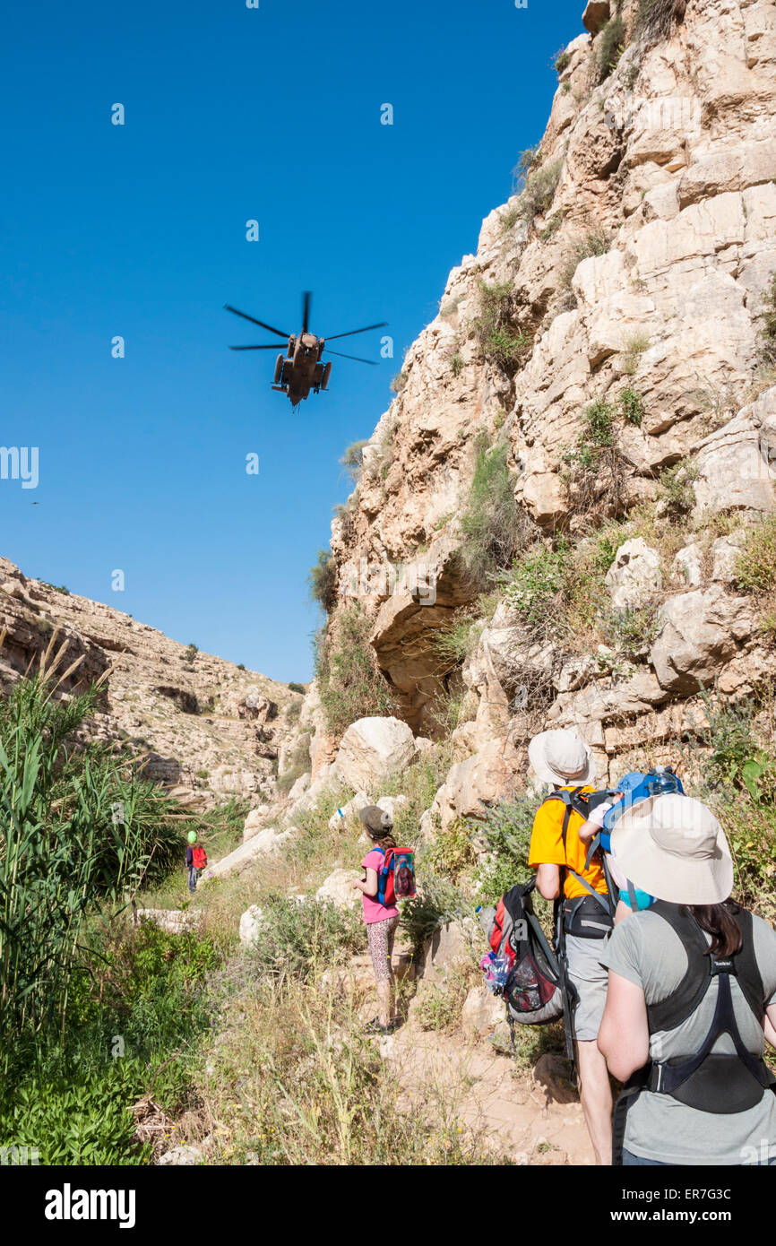 Israël. Les randonneurs d'oeil à un hélicoptère de sauvetage militaire, volant bas au-dessus du Kelt canyon dans la Judée désert. Banque D'Images