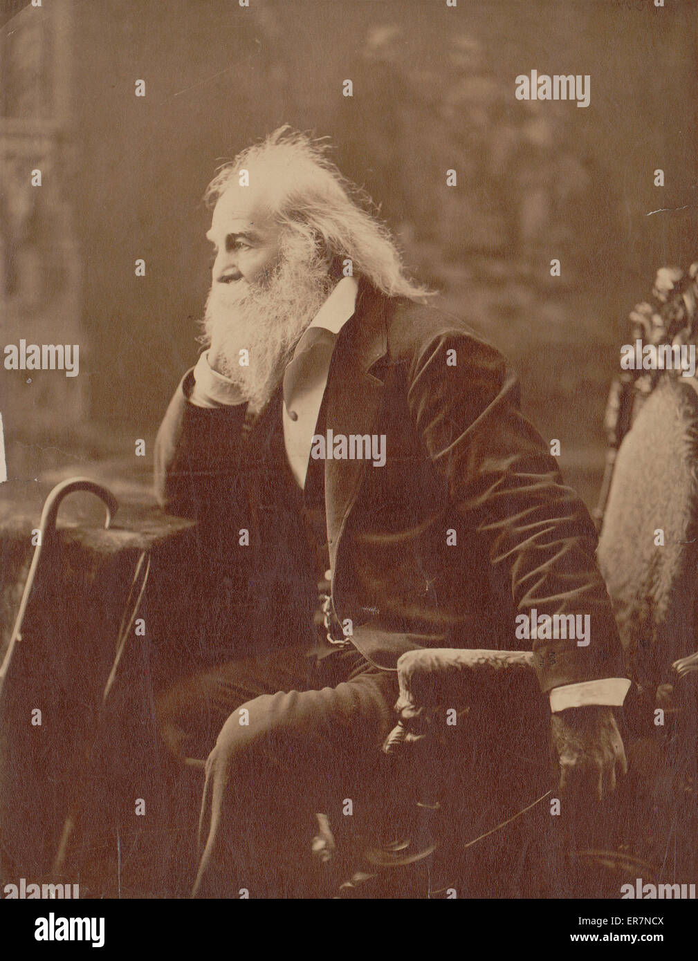 Walt Whitman, trois-quart portrait en pied, assis, face vers la gauche avec le coude et canne à proximité reposant sur une table. Date 1881. Banque D'Images