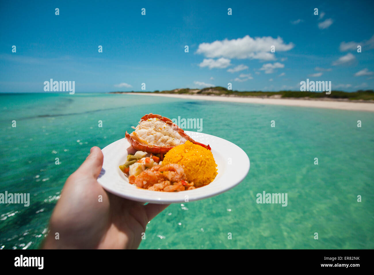 Un homme est titulaire d'un plateau de fruits de mer avec crevettes, queue de homard, et tandis que le riz assaisonné sur un bateau Banque D'Images