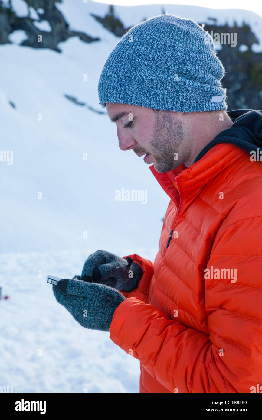 Un grimpeur vérifie ses e-mails sur son smartphone tout en camping dans les montagnes. Banque D'Images