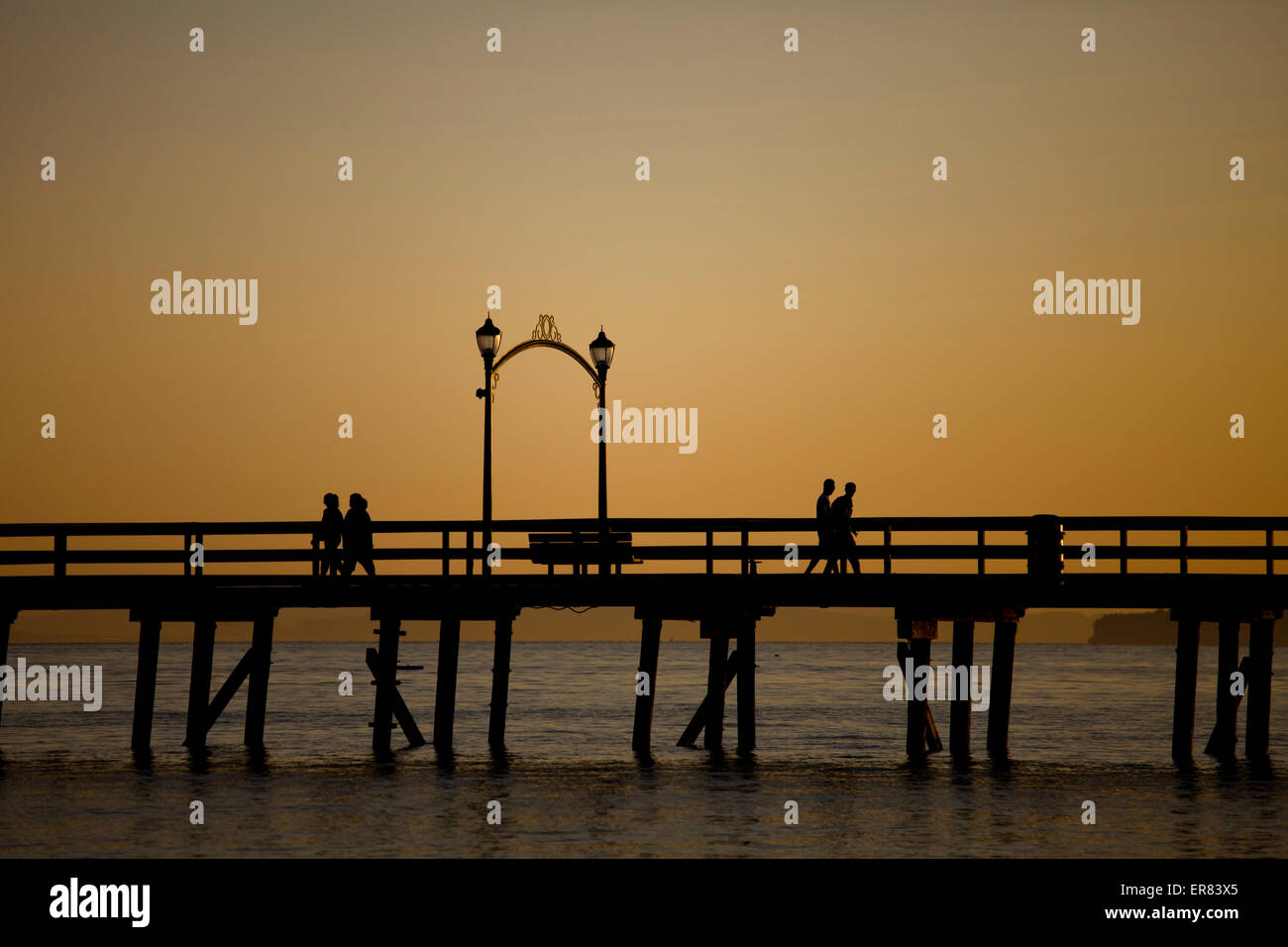 Les visiteurs marchent le quai après le coucher du soleil à White Rock (Colombie-Britannique). Banque D'Images