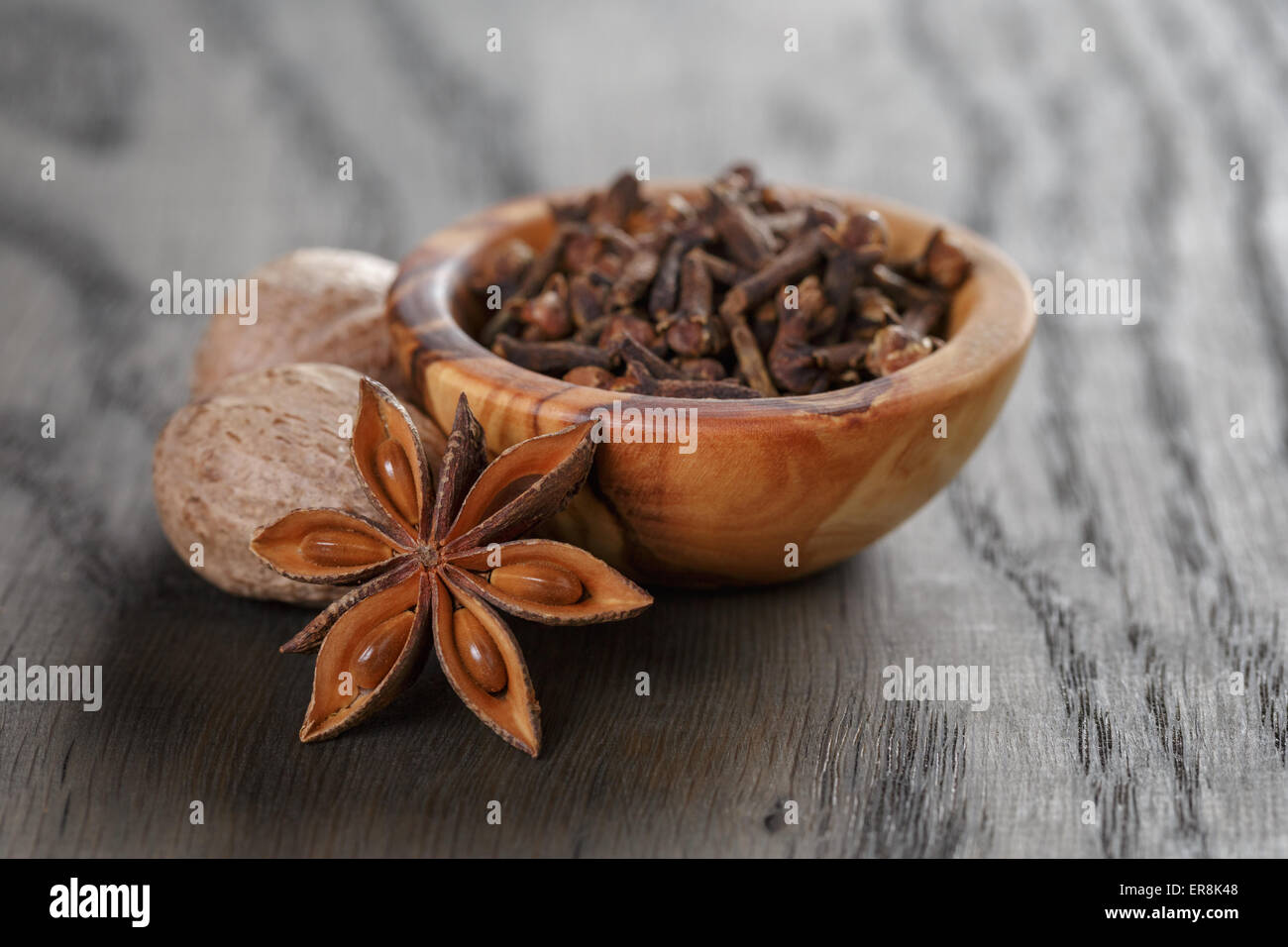 Les étoiles d'anis et de girofle Muscade dans bol d'olive sur la table en chêne, rustique Banque D'Images